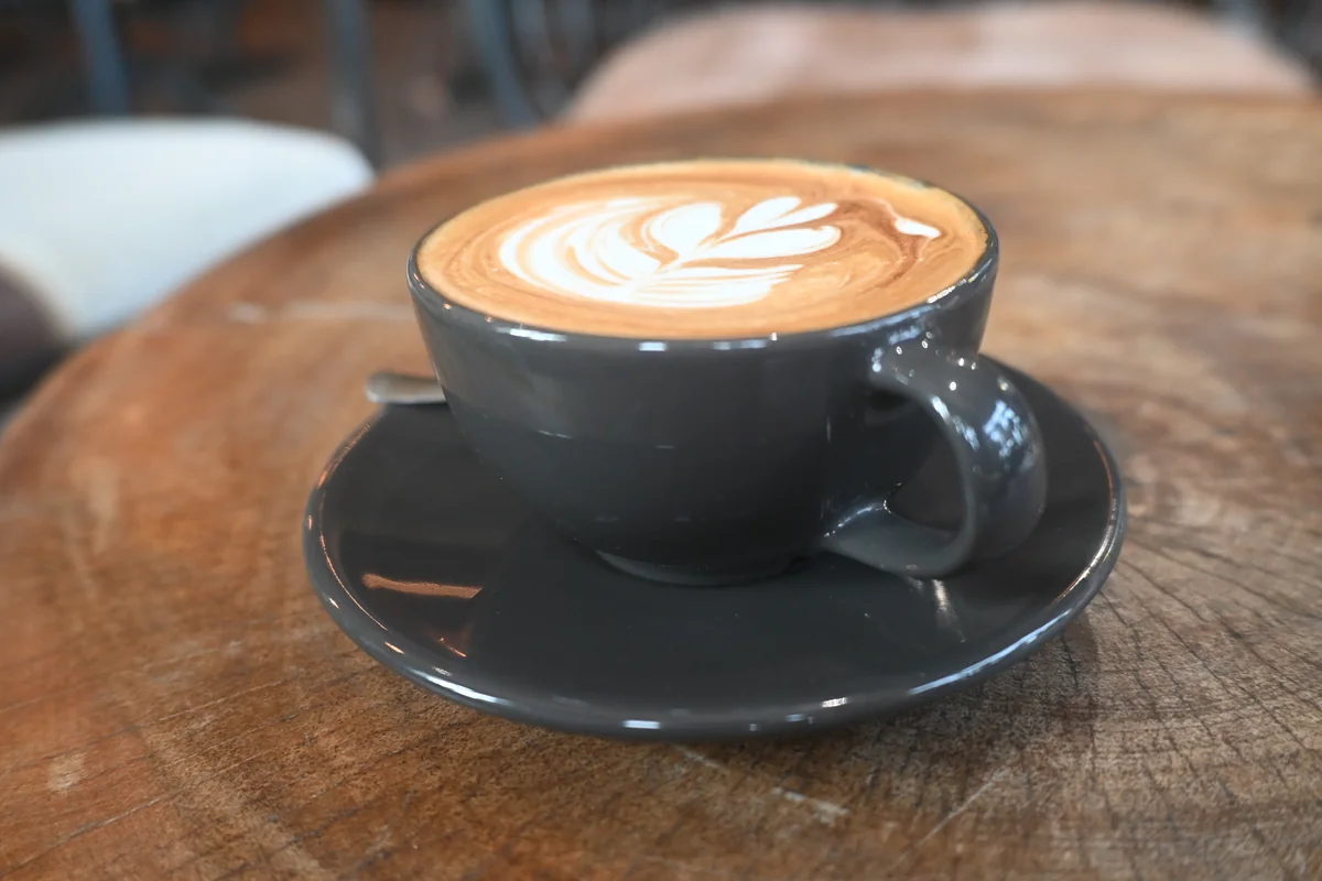 Latte art in a dark ceramic cup on a wooden café table in Pattaya